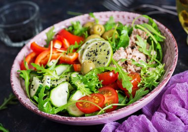 Ton balıklı salata domates, zeytin, salatalık, tatlı biber ve roka rustik arka plan üzerinde