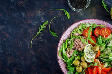 Ton balıklı salata domates, zeytin, salatalık, tatlı biber ve roka rustik arka plan üzerinde