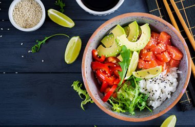 Hawaii somon balığı kasesi, pilav, avokado, paprika, susam tohumu ve limon. Buda kasesi. Diyet yemek. Üst görünüm