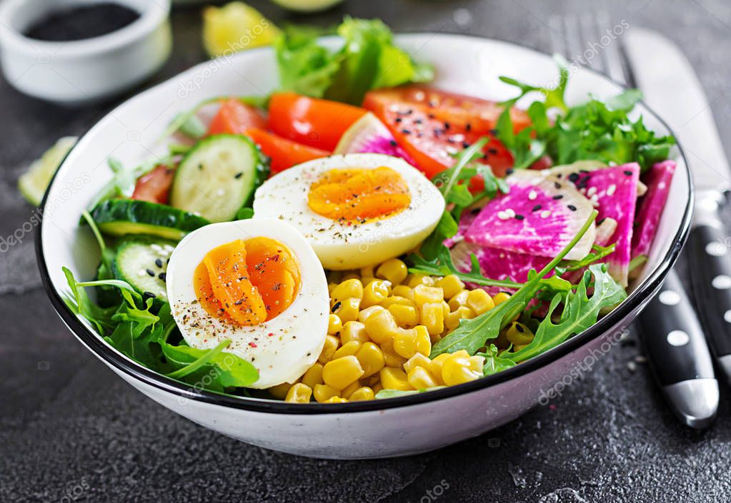 Bowl with fresh cucumber, tomato, watermelon radish, lettuce, arugula, corn and boiled egg