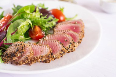 Bir plaka üzerinde taze sebze salatası ile Japon geleneksel salata adet pişmiş Izgara Ahi tuna ve susam ile. Otantik Japon yemekleri.