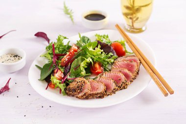 Bir plaka üzerinde taze sebze salatası ile Japon geleneksel salata adet pişmiş Izgara Ahi tuna ve susam ile. Otantik Japon yemekleri.