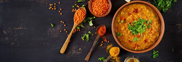 Indian dal. Food. Traditional Indian soup lentils.  Indian Dhal spicy curry in bowl, spices, herbs, rustic black wooden background. Top view. Authentic Indian dish. Overhead. Banner