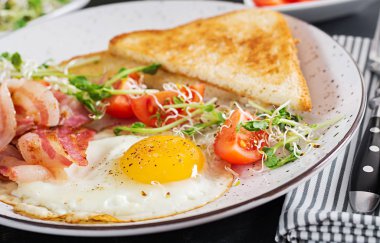 İngiliz kahvaltısı - ekmek, yumurta, domuz pastırması ve domates ve microgreens salata.