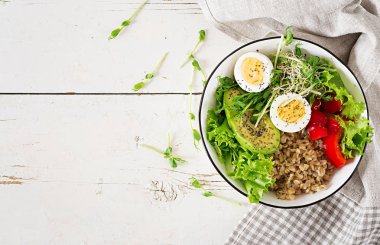 Taze salata. Kahvaltı kase yulaf ezmesi, kırmızı biber, avokado, marul, microgreens ve haşlanmış yumurta. Sağlıklı gıda. Vejetaryen Buda kase. Üstten Görünüm