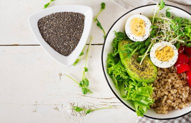 Taze salata. Kahvaltı kase yulaf ezmesi, kırmızı biber, avokado, marul, microgreens ve haşlanmış yumurta. Sağlıklı gıda. Vejetaryen Buda kase. Üstten Görünüm