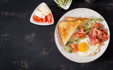 İngiliz kahvaltısı - ekmek, yumurta, domuz pastırması ve domates ve microgreens salata. Üstten Görünüm. Düz yatıyordu