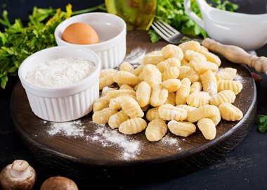 Pişmemiş ev yapımı Gnocchi maydanoz koyu arka plan üzerinde bir kapta bir mantar krema sos ile.