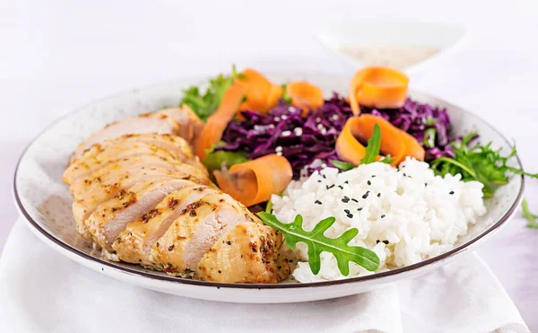 Healthy salad. Buddha bowl dish with chicken fillet, rice,  red cabbage, carrot, fresh lettuce salad and sesame. Healthy balanced eating.