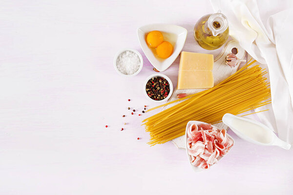 Ингредиенты для приготовления пасты из карбонары, спагетти с панчеттой, яйцом, перцем, солью и твердым сыром пармезан. Итальянская кухня. Паста алла карбонара. Вид сверху, плоский, копировальное пространство

