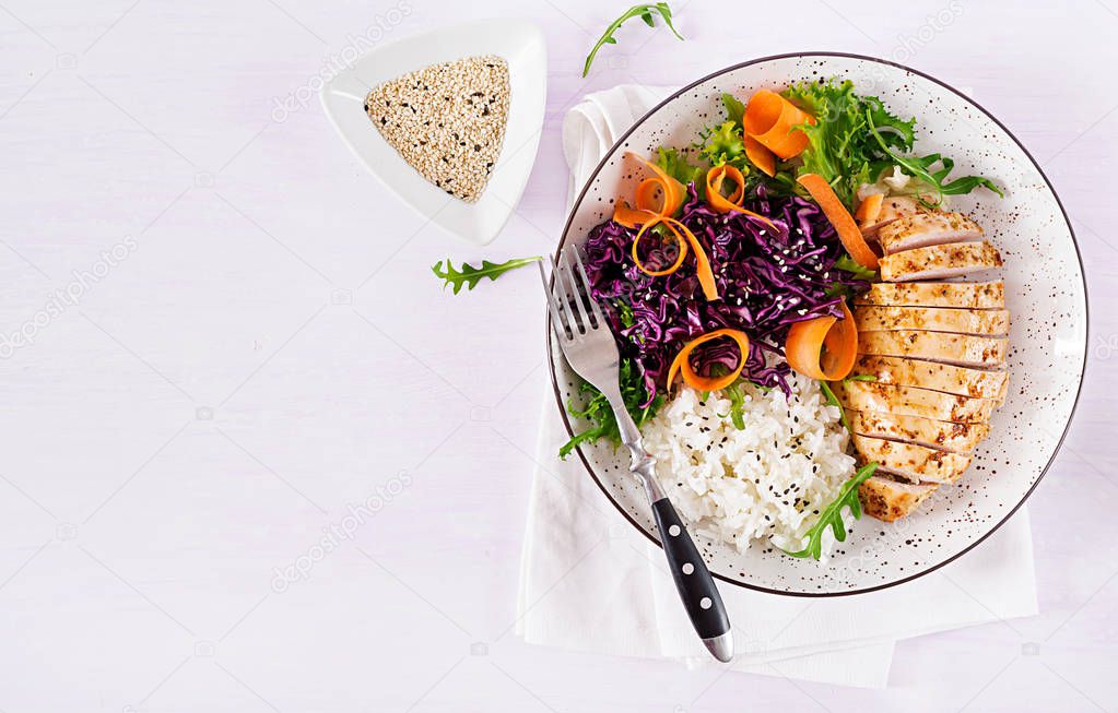 Healthy salad. Buddha bowl dish with chicken fillet, rice,  red cabbage, carrot, fresh lettuce salad and sesame. Healthy balanced eating. Top view.
