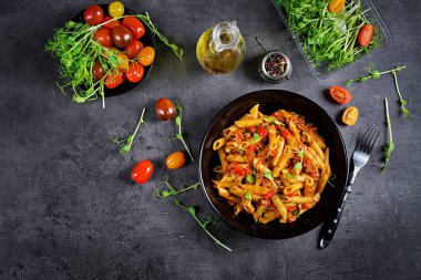 Domates, etli domates soslu Penne makarna, dekore bezelye lahanası karanlık bir masaya. Üstten Görünüm