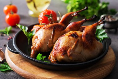 Karanlık bir arka plan üzerinde tavada pişmiş bıldırcınlar