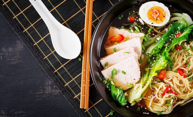 Koyu arka plan üzerinde bir kapta yumurta, domuz eti ve pak choi lahana ile miso Ramen Asya erişte. Japon mutfağı. Üstten Görünüm. Düz yatıyordu