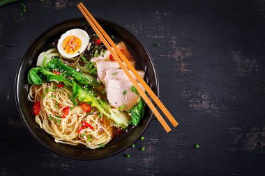 Koyu arka plan üzerinde bir kapta yumurta, domuz eti ve pak choi lahana ile miso Ramen Asya erişte. Japon mutfağı. Üstten Görünüm. Düz yatıyordu