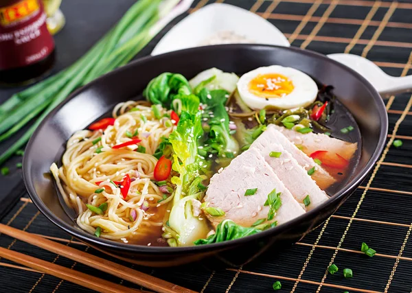 Miso Ramen Asian noodles with egg, pork and pak choi cabbage in bowl on dark background. Japanese cuisine.