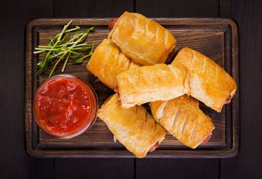 Domates soslu bir ahşap tahta üzerinde hamur sosis. Üstten Görünüm