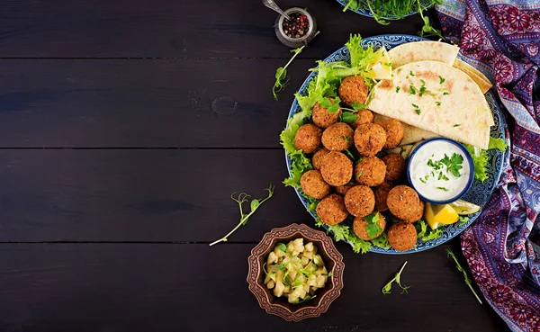 Falafel, hummus and pita. Middle eastern or arabic dishes on a dark background. Halal food. Top view. Copy space
