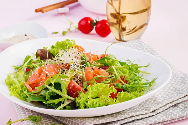 Diet menu. Healthy salad of fresh vegetables - tomatoes, avocado, arugula, seeds and salmon on a bowl. Vegan food.