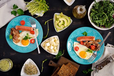 İngiliz kahvaltısı - kızarmış yumurta, domates, sosis ve pastırma. Üstte görüntü