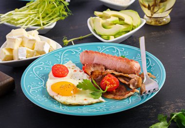 İngiliz kahvaltısı - kızarmış yumurta, domates, sosis ve pastırma.