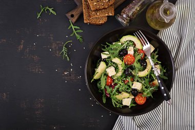 Dilimlenmiş avokado, kiraz domates, siyah zeytin ve peynir ile yeşil salata. Sağlıklı diyet vejetaryen yaz sebze salatası. Masa ayarı. Gıda konsepti. Üstte görüntü.