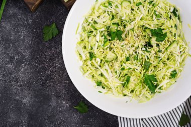 Sağlıklı salata. Koyu masada lahana, salatalık, yeşil soğan ve maydanoz ile Bahar vegan salata. Üstte görüntü