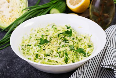 Sağlıklı salata. Koyu masada lahana, salatalık, yeşil soğan ve maydanoz ile Bahar vegan salata.