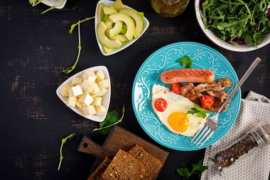 İngiliz kahvaltısı - kızarmış yumurta, domates, sosis ve pastırma. Üstte görüntü