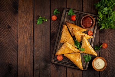 Asya yemekleri. Samsa (samosas) ahşap arka plan üzerinde tavuk fileto ve peynir ile. Üstte görüntü