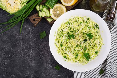 Sağlıklı salata. Koyu masada lahana, salatalık, yeşil soğan ve maydanoz ile Bahar vegan salata. Üstte görüntü