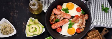 İngiliz kahvaltısı - kızarmış yumurta, domates, sosis ve pastırma. Afiş. Üstte görüntü