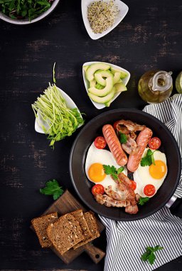 İngiliz kahvaltısı - kızarmış yumurta, domates, sosis ve pastırma. Üstte görüntü