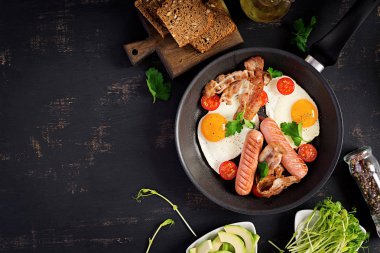 İngiliz kahvaltısı - kızarmış yumurta, domates, sosis ve pastırma. Üstte görüntü