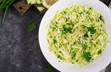 Sağlıklı salata. Koyu masada lahana, salatalık, yeşil soğan ve maydanoz ile Bahar vegan salata. Üstte görüntü