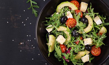 Dilimlenmiş avokado, kiraz domates, siyah zeytin ve peynir ile yeşil salata. Sağlıklı diyet vejetaryen yaz sebze salatası. Masa ayarı. Gıda konsepti. Üstte görüntü.