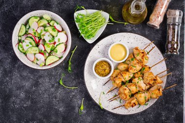Izgara tavuk kebap ve salatalık, turp, koyu bir arka plan üzerinde soğan ile salata. Kopya alanı. Üstte görüntü