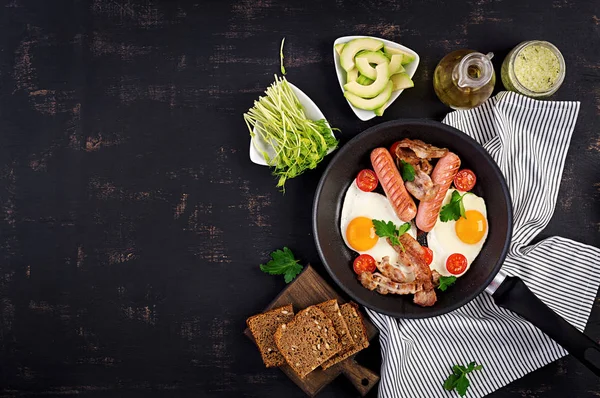 İngiliz kahvaltısı - kızarmış yumurta, domates, sosis ve pastırma. Üstte görüntü