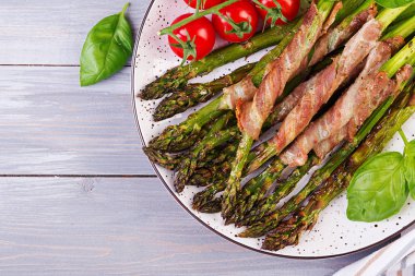 Izgara yeşil kuşkonmaz ahşap masada pastırma ile sarılmış. Üstte görüntü