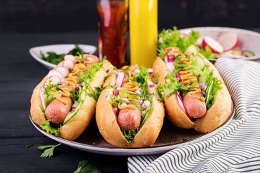 Sosis, salatalık, turp ve marul koyu ahşap arka plan üzerinde sosisli sandviç. Yaz sosislisandviçi.