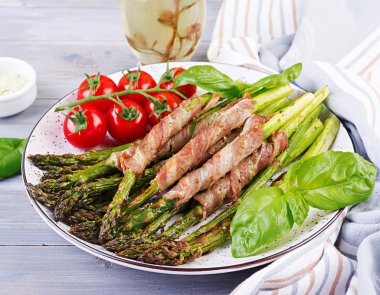 Izgara yeşil kuşkonmaz ahşap masada pastırma ile sarılmış.