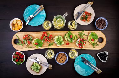 Sağlıklı vejetaryen yemek masası ayarı Düz yatıyordu. Domates, salatalık, avokado, çilek, otlar ve zeytin, aperatifler ile Sandviçler. Temiz beslenme, vegan gıda