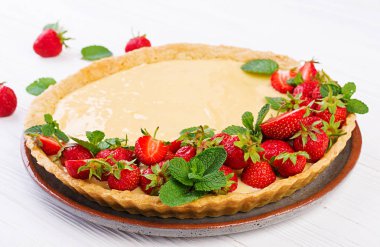 Hafif arka planda nane yaprakları ile süslenmiş çilek ve krem şanti ile Tart.