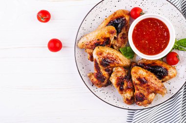 Asya tarzında pişmiş tavuk kanatları ve tabakta domates sosu. Üstte görüntü