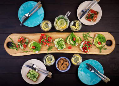 Sağlıklı vejetaryen yemek masası ayarı Düz yatıyordu. Domates, salatalık, avokado, çilek, otlar ve zeytin, aperatifler ile Sandviçler. Temiz beslenme, vegan gıda