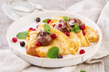 Nane yaprağı ile süslenmiş çilek ve çikolata ile krep. Lezzetli kahvaltı.