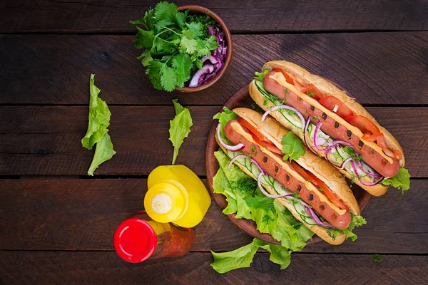 Hot Dog Kolbásszal Uborka Paradicsom Saláta Sötét Fából Készült Háttérrel — Stock Fotó