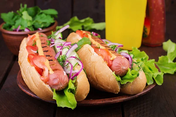 Hot dog with  sausage, cucumber, tomato and lettuce on dark wood — Stock Photo, Image
