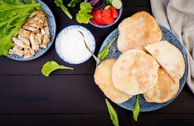 Pide tavuk, domates ve marul ahşap arka plan ile doldurulmuş. Orta Doğu mutfağı. Üstte görüntü