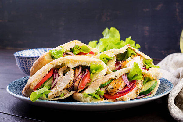 Пита фаршированная курицей, помидорами и салатом на деревянном фоне. Ближневосточная кухня
.